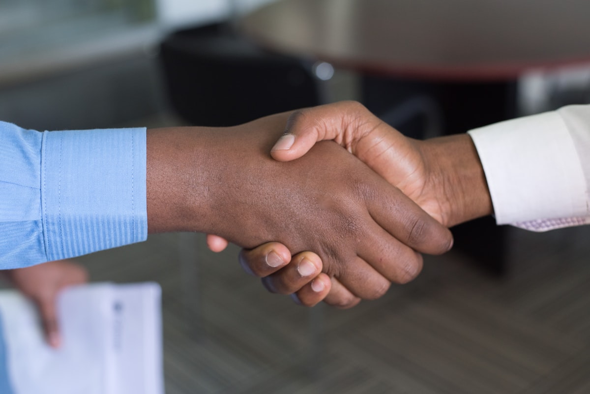 Deux personnes se serrent la main, symbolisant la confiance entre un artisan et son client.