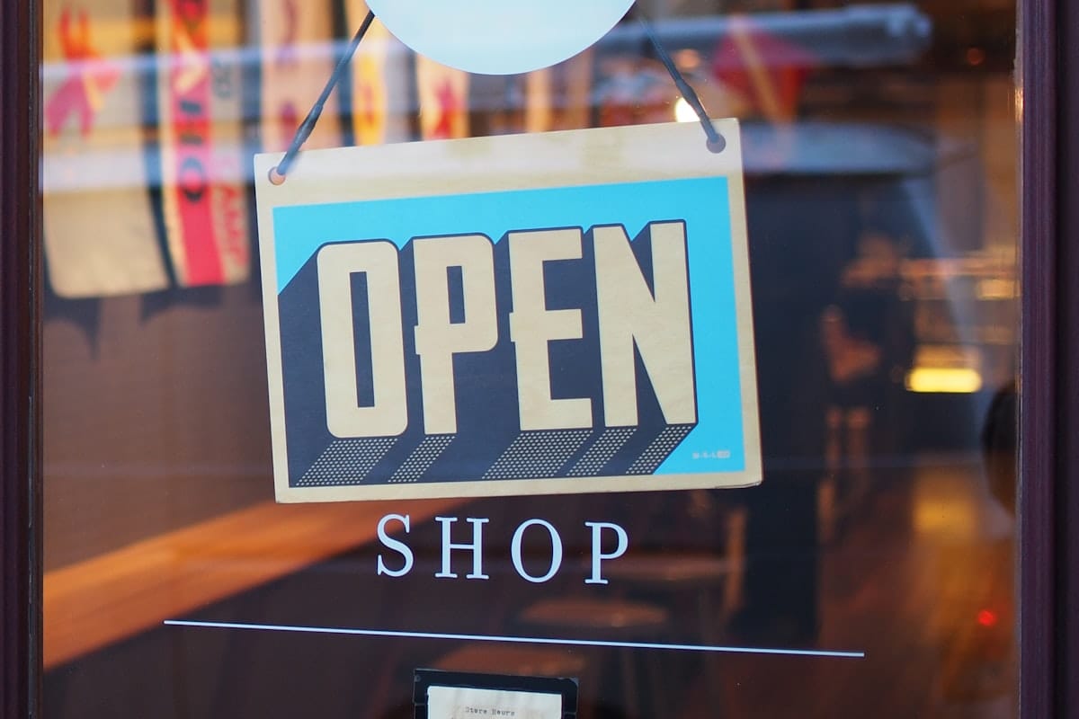 Une enseigne lumineuse Open bleue et grise signalant qu'un commerce est ouvert, symbole de visibilité en ligne et hors ligne.