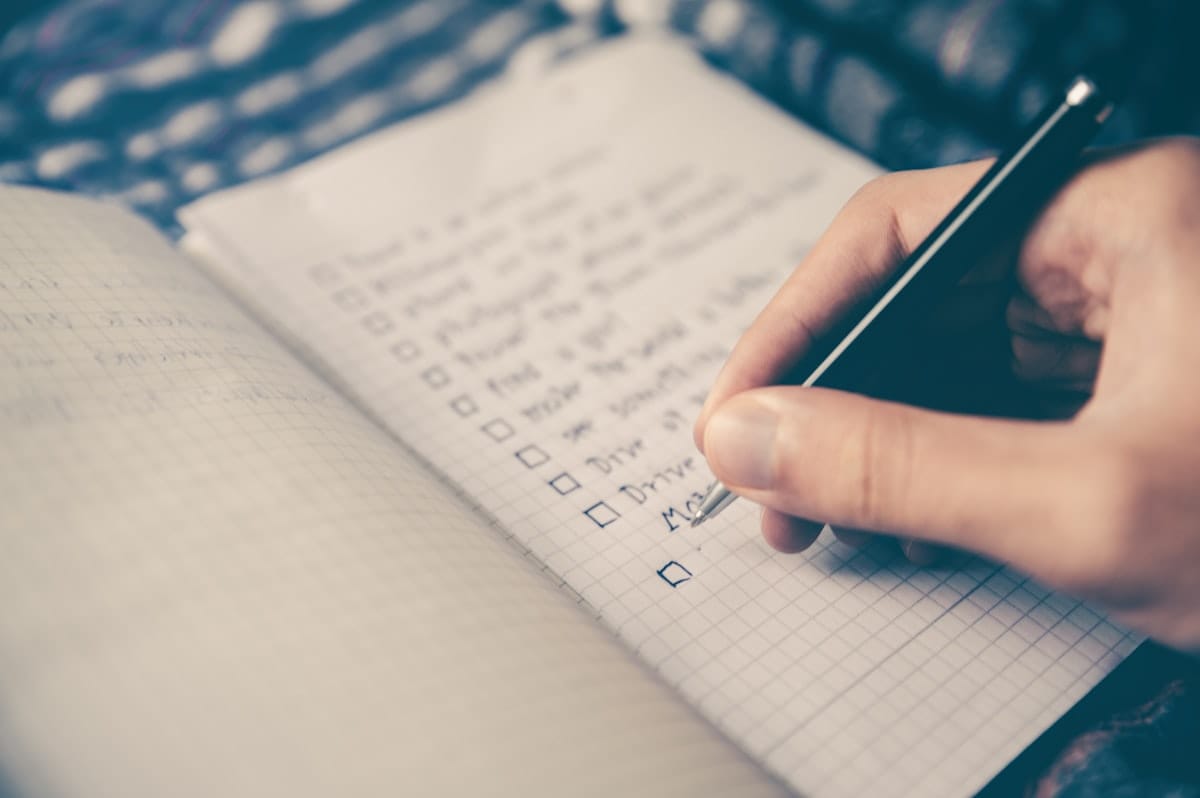 Pourquoi mon site ne génère pas de devis ? 5 Une personne écrit sur un carnet, illustrant le remplissage d'un formulaire de contact ou de demande de devis.