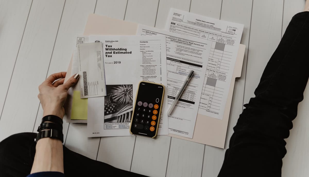 Une personne tient un papier près d'un stylo et d'une calculatrice, illustrant l'analyse d'un devis pour un site internet.
