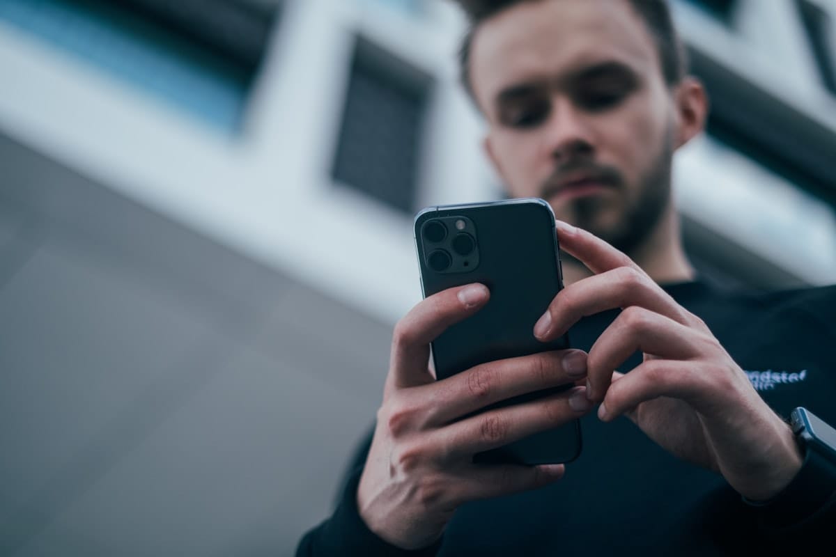 Pourquoi mon site ne génère pas de devis ? 4 Un homme en pull noir consulte son smartphone, illustrant le test des 5 secondes pour comprendre une offre sur mobile.