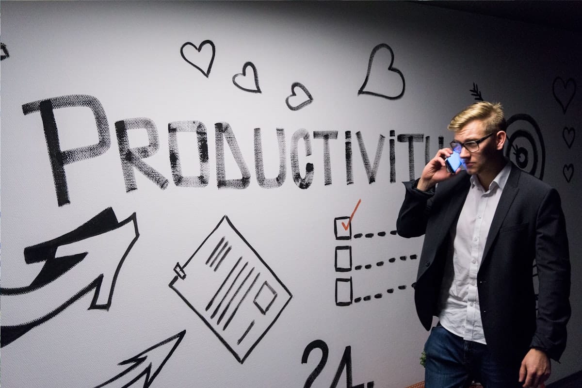 Un homme tient son smartphone face à un mur d'organisation, illustrant la vérification d'une fiche Google fraîchement créée.