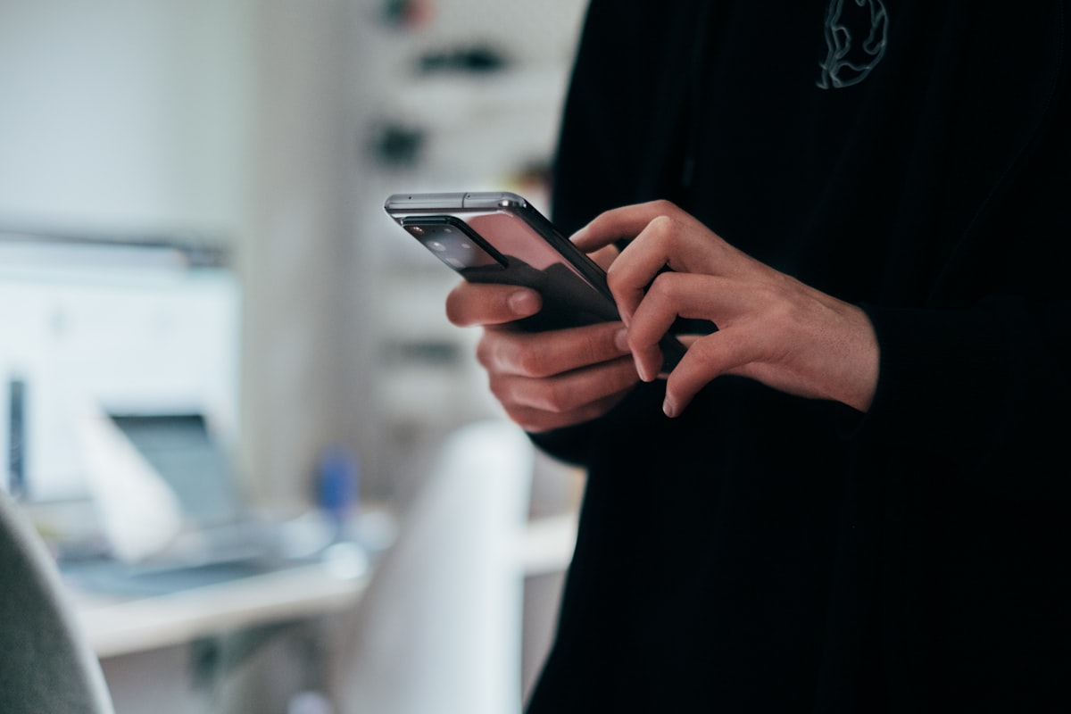 Une personne tient un smartphone Android noir, illustrant la vérification de la visibilité d'un site sur mobile.